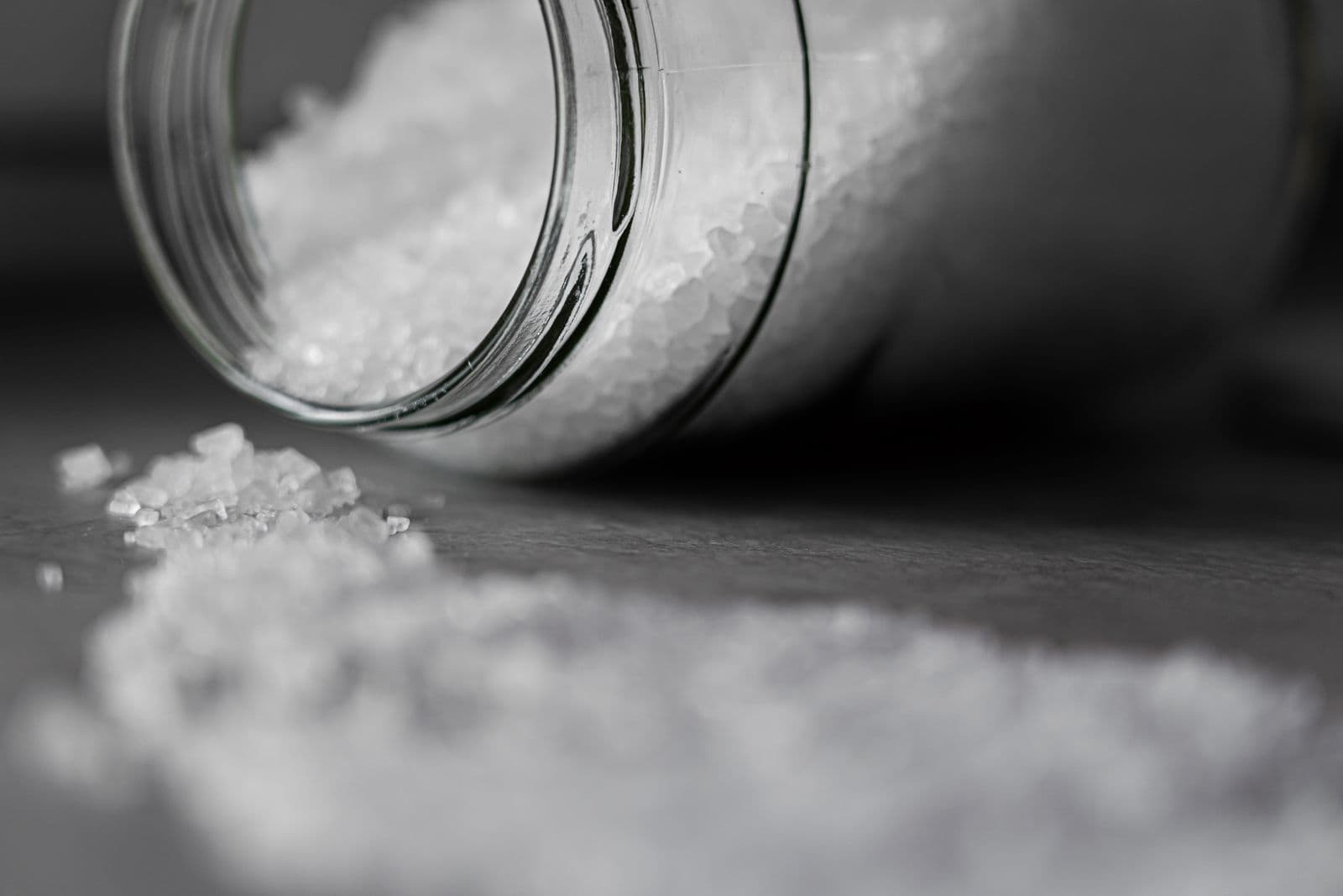 Coarse rock salt pouring from a glass jar