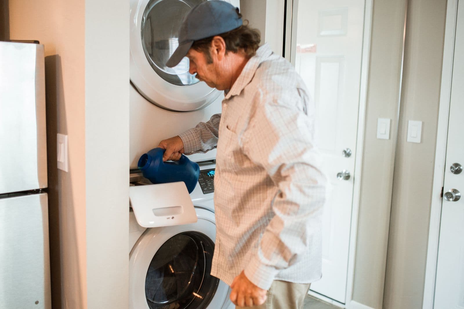 Person adding detergent at a stacked washer and dryer in a laundry room