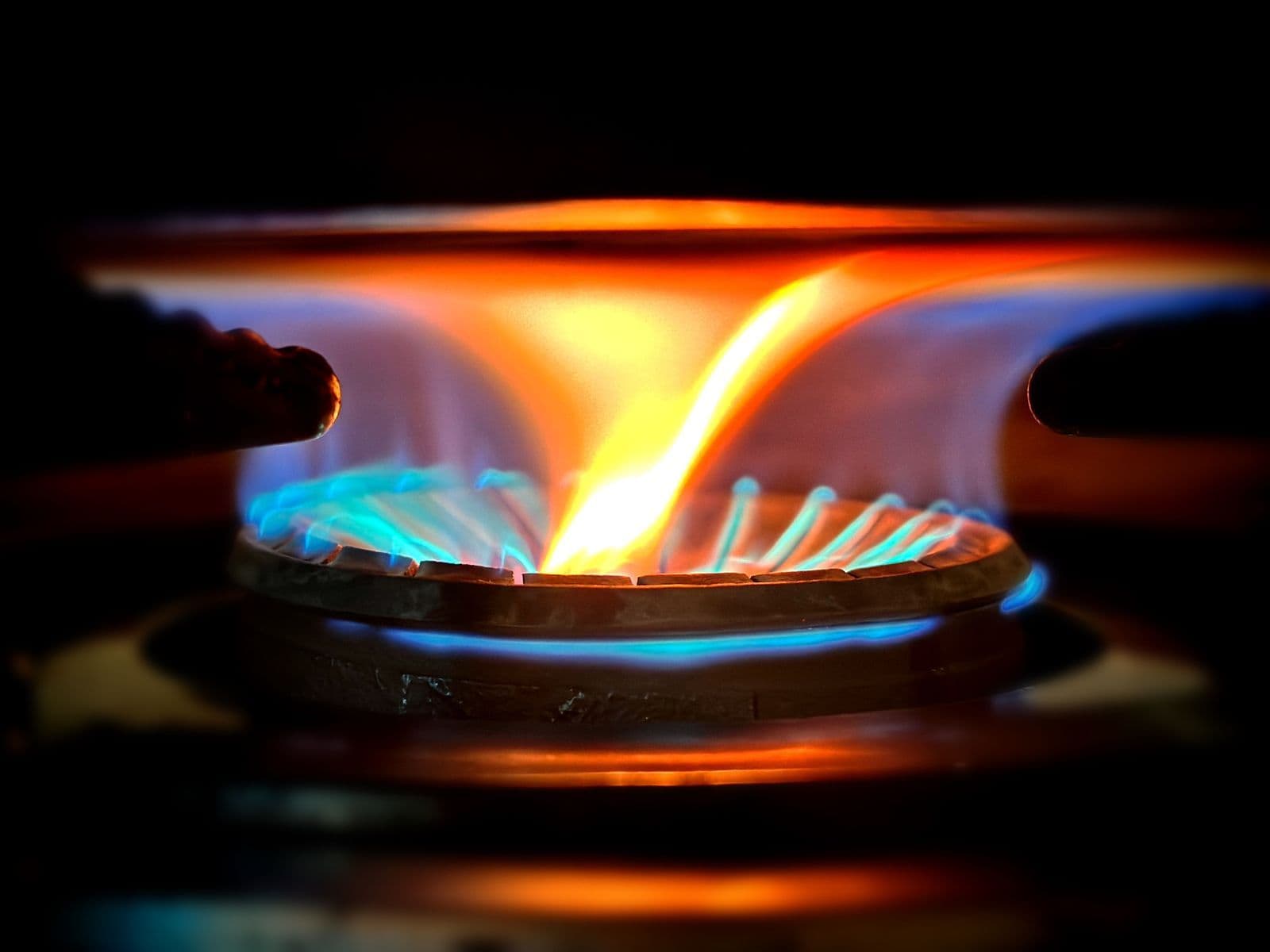 Close-up of blue and orange flames on a gas range burner