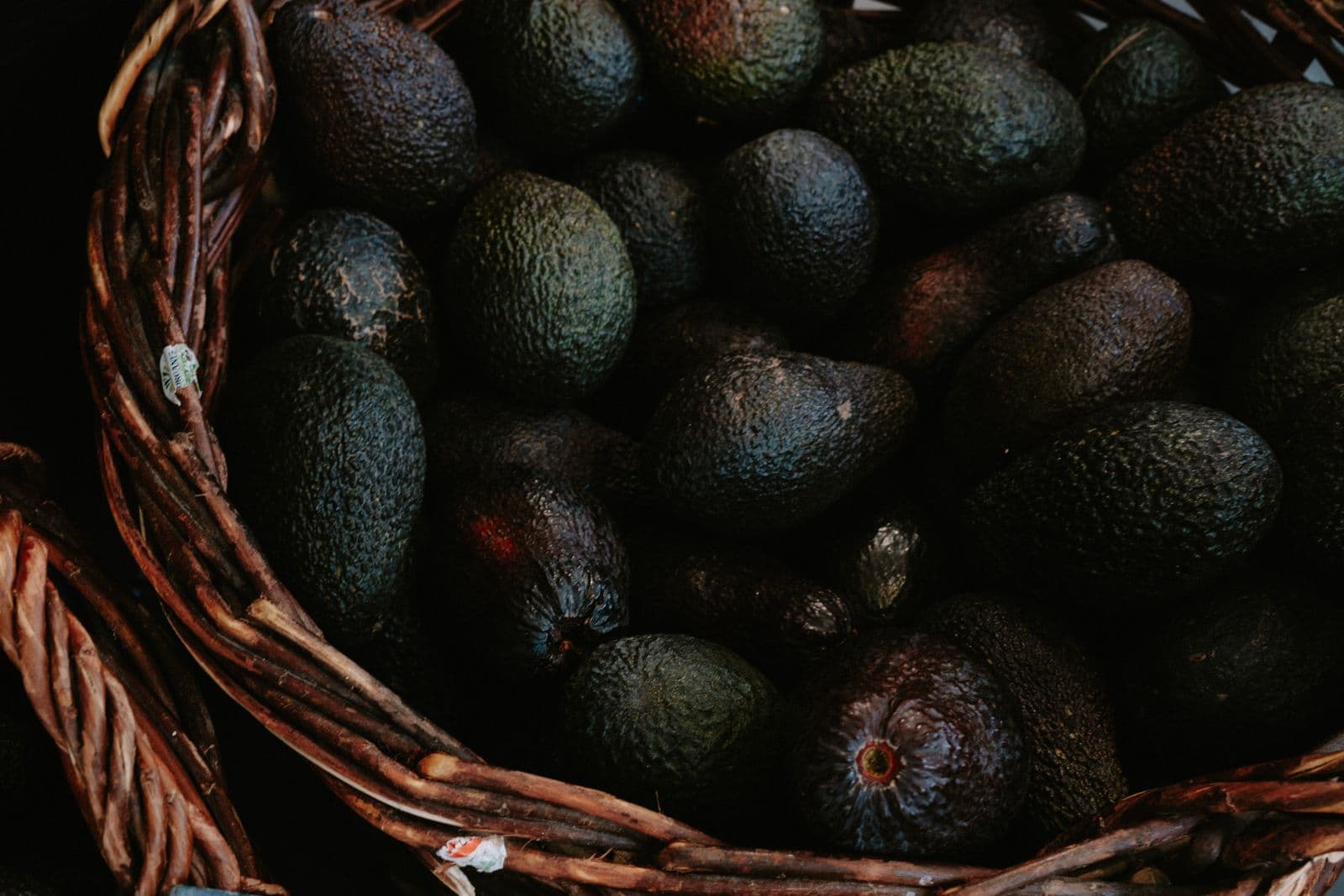 Fresh avocados piled in a wicker basket